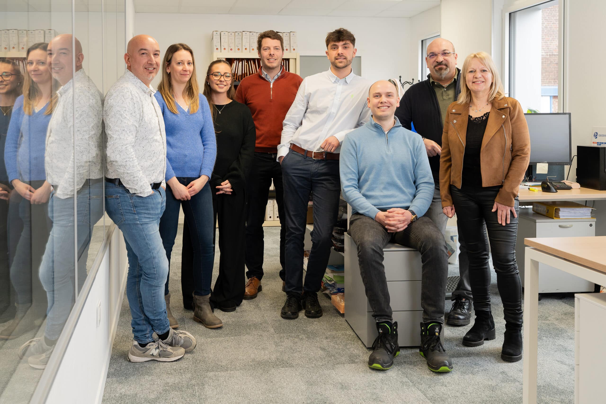Huit collaborateurs des services administratifs et commerciaux de Manergo posant souriants dans l'espace bureaux de l'entreprise.