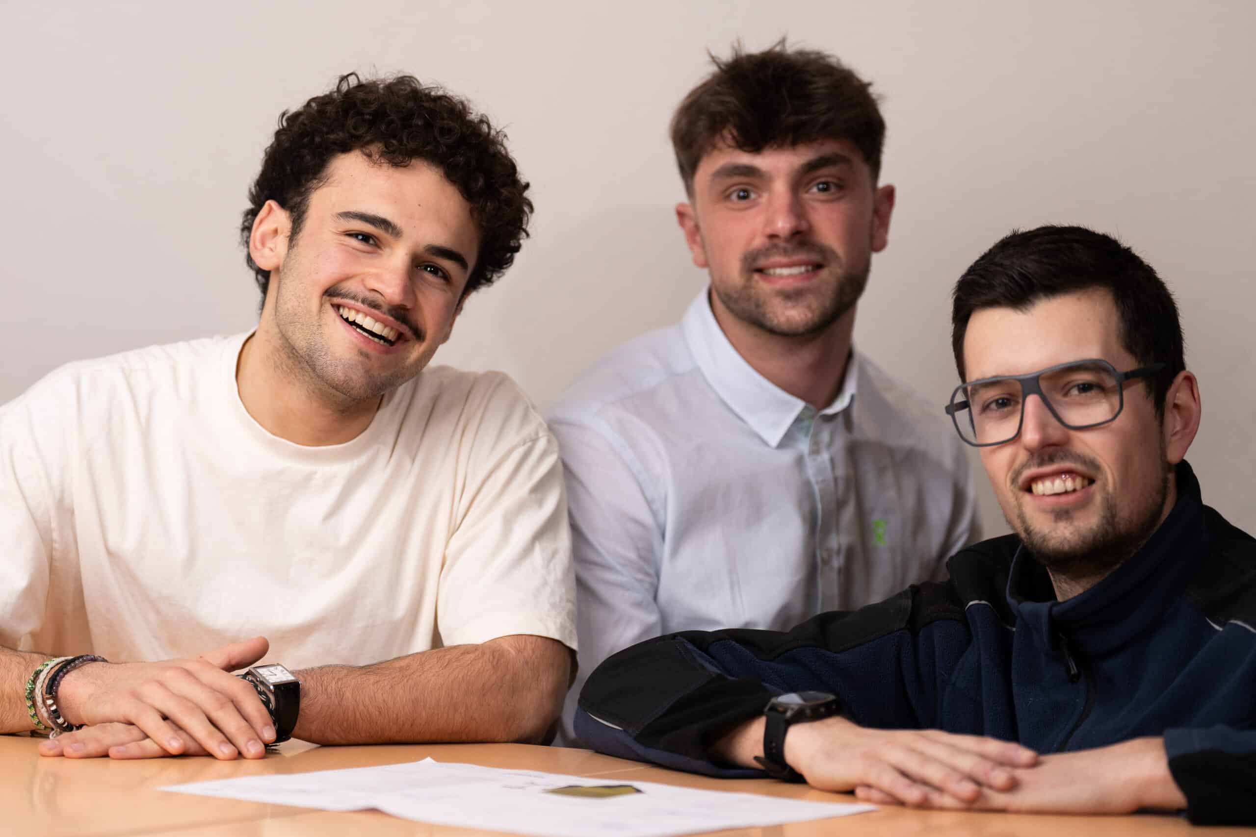 Trois concepteurs du bureau d'études Manergo souriants, réunis autour d'une table devant un plan technique d'appareil de manutention.